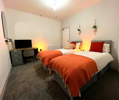 two beds in a room with a desk and a computer at SA Stays in Wigan