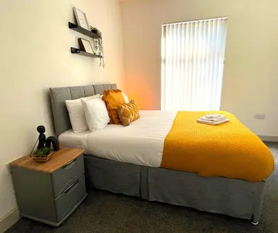 a bedroom with a large bed with a yellow blanket at SA Stays in Wigan