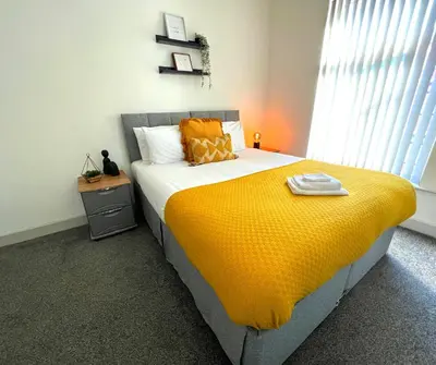 a bedroom with a large bed with a yellow blanket at SA Stays in Wigan