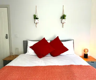 a bed with two red pillows on top of it at SA Stays in Wigan