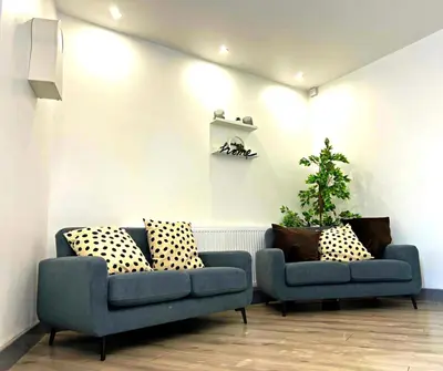 a living room with two blue couches and a plant at SA Stays in Wigan