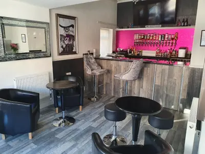 a bar with black stools and a pink wall at The Dudley Hotel in Blackpool