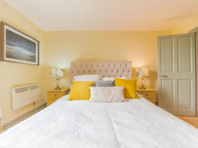a bedroom with a large white bed with yellow pillows at Mop Fair Sunny Garden Town Centre - Pass the Keys in Ulverston