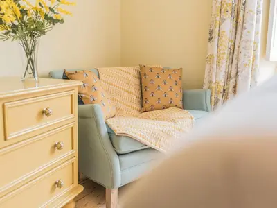 a bedroom with a blue chair and a dresser at Mop Fair Sunny Garden Town Centre - Pass the Keys in Ulverston