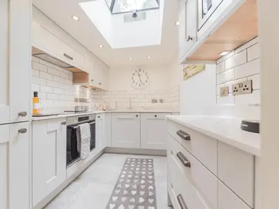 a kitchen with white cabinets and a skylight at Mop Fair Sunny Garden Town Centre - Pass the Keys in Ulverston