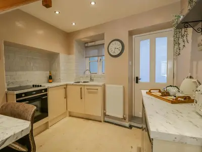 a kitchen with a sink and a clock on the wall at Endgill Cottage in Ulverston