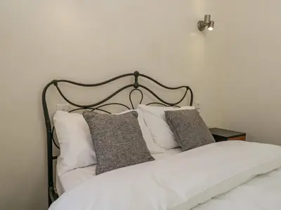 a bed with a black headboard and white pillows at Endgill Cottage in Ulverston