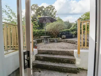 an open door to a patio with an umbrella at Endgill Cottage in Ulverston