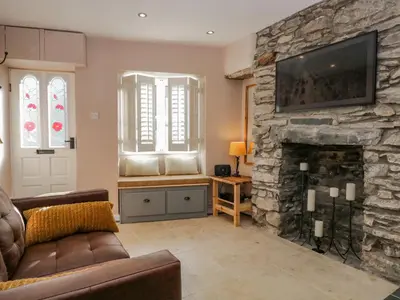 a living room with a couch and a stone fireplace at Endgill Cottage in Ulverston