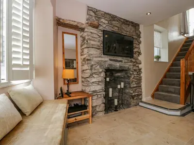 a living room with a stone fireplace with a tv at Endgill Cottage in Ulverston