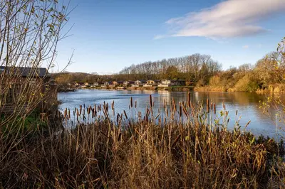 a view of a river with houses in the distance at Lakeland Lodge in Carnforth