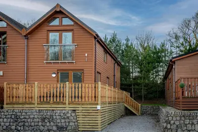 a large wooden house with a wooden deck at Lakeland Lodge in Carnforth
