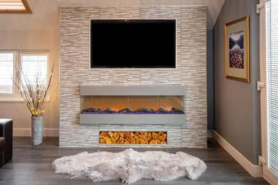 a living room with a fireplace with a tv above it at Lakeland Lodge in Carnforth