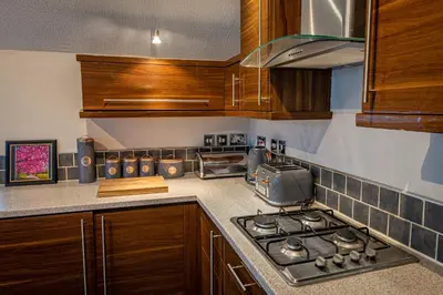 a kitchen with wooden cabinets and a stove top oven at Lakeland Lodge in Carnforth