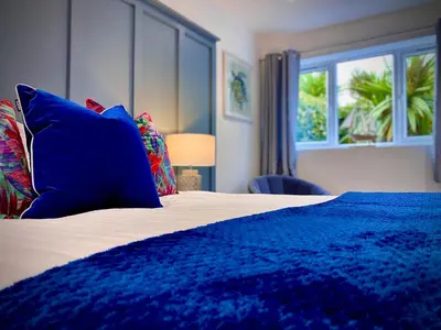 a bedroom with a blue bed with pillows and a window at Beautiful Hot Tub Suite in Lytham St Annes in Lytham St Annes