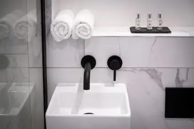 a bathroom with a sink and towels on a shelf at Dalton Sq Apartments in Lancaster
