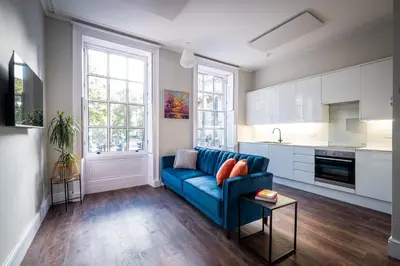 a living room with a blue couch and a kitchen at Dalton Sq Apartments in Lancaster