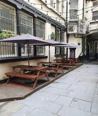 a group of picnic tables with umbrellas in front of a building at L2 Apartments- City Center- 2 bed in Liverpool