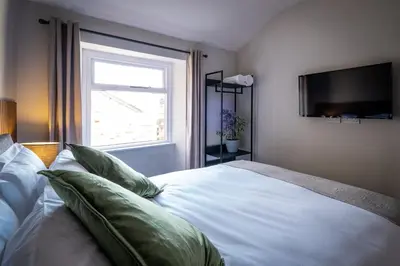 a bedroom with a white bed with pillows and a window at Dalton Sq Apartment 2 in Lancaster