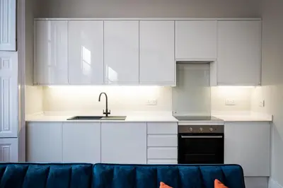 a kitchen with white cabinets and a blue couch at Dalton Sq Apartment 2 in Lancaster