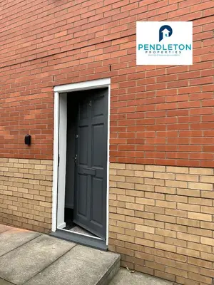 a door leading into a brick building with a sign at Cosy Central APT, 10 Min Walk to UCLAN and Library in Preston