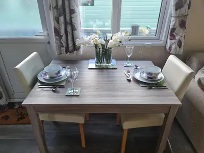 a wooden table with chairs and a vase of flowers at Nicks and Carmels by the Lake in Carnforth