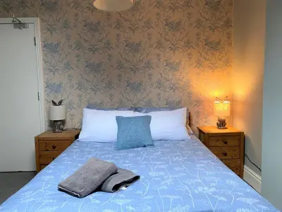 a bed with a blue comforter and two pillows on it at Villa with Park Views close to Liverpool Centre in Liverpool