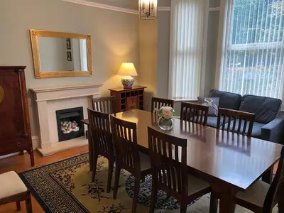 a living room with a table and chairs and a fireplace at Villa with Park Views close to Liverpool Centre in Liverpool