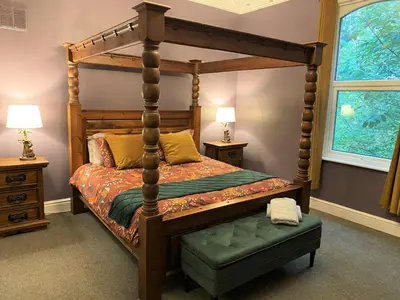a bedroom with a wooden canopy bed with a ottoman at Villa with Park Views close to Liverpool Centre in Liverpool