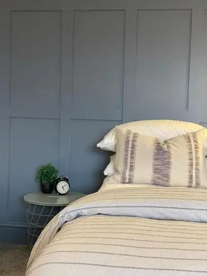 a bed with a pillow and a clock on a table at Deluxe Huge Detached House with Parking, sleeps up to 30 people, 2m from Liverpool City Centre in Liverpool