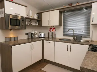 a kitchen with white cabinets and a microwave at 3 Yealands in Carnforth