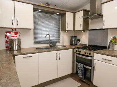 a kitchen with white cabinets and a stove top oven at 3 Yealands in Carnforth