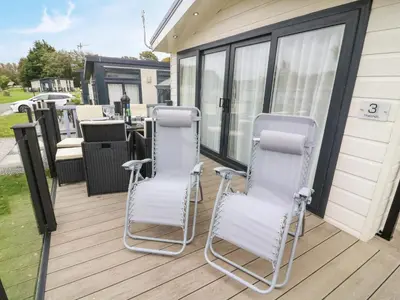 two chairs sitting on a deck with a table at 3 Yealands in Carnforth