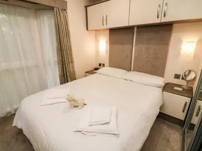 a bedroom with a white bed with two towels on it at 3 Yealands in Carnforth