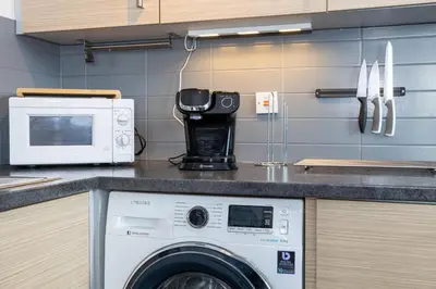 a kitchen with a washing machine and a microwave at GuestReady - Modern stay in Bispham House in Liverpool