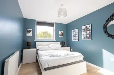 a bedroom with blue walls and a white bed at GuestReady - Modern stay in Bispham House in Liverpool