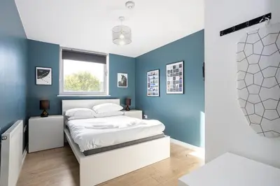 a bedroom with blue walls and a white bed at GuestReady - Modern stay in Bispham House in Liverpool