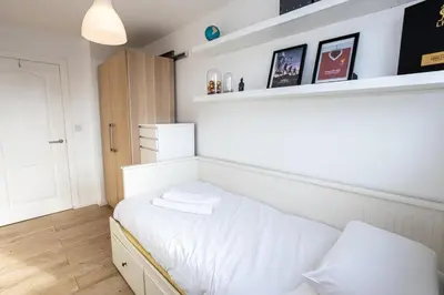 a small bedroom with a bed with white sheets at GuestReady - Modern stay in Bispham House in Liverpool