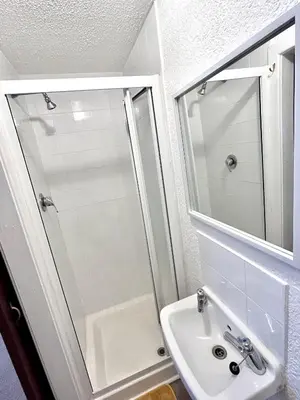a white bathroom with a shower and a sink at Aysgarth House in Blackpool