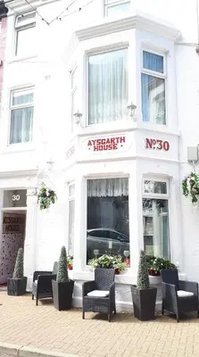 a white building with chairs in front of a store at Aysgarth House in Blackpool