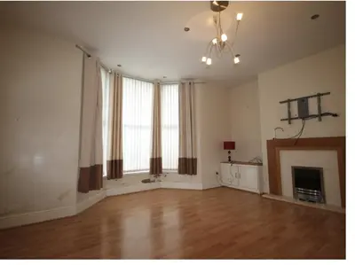 an empty living room with a fireplace and a chandelier at Beech Apparent lovely spacious double room in Liverpool