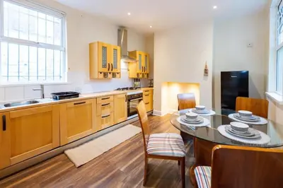 a kitchen with wooden cabinets and a table and chairs at Beech Apparent lovely spacious double room in Liverpool