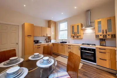 a kitchen with a glass table and wooden cabinets at Beech Apparent lovely spacious double room in Liverpool