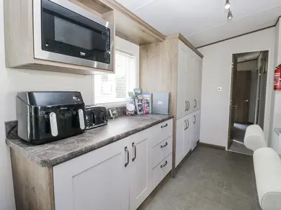 a kitchen with white cabinets and a microwave at Lilac Lodge in Carnforth