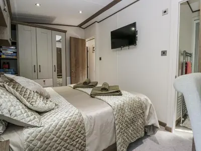 a bedroom with a bed with a television on the wall at Lilac Lodge in Carnforth