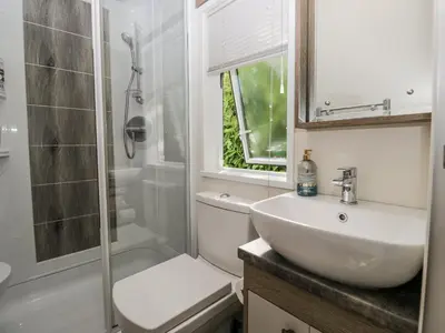 a white bathroom with a sink and a shower at Lilac Lodge in Carnforth