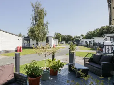 a deck with furniture and plants on a residential street at Lilac Lodge in Carnforth