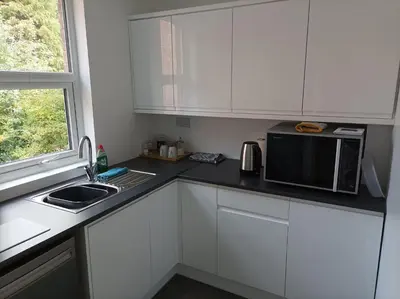 a kitchen with white cabinets and a microwave and a sink at Victorian Renovation Room 1 in Liverpool
