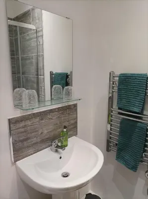 a white sink in a bathroom with a mirror and towels at Victorian Renovation Room 4 in Liverpool