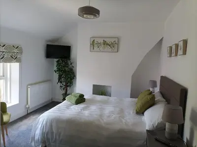 a bedroom with a large white bed with green pillows at Victorian Renovation Room 5 in Liverpool